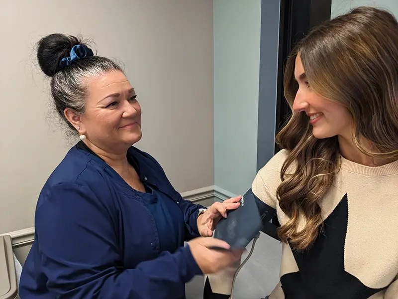 Happy Nurse Placing Blood Pressure Cuff on Smiling Patient