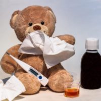 A teddy bear propped up to look like they have the flu.